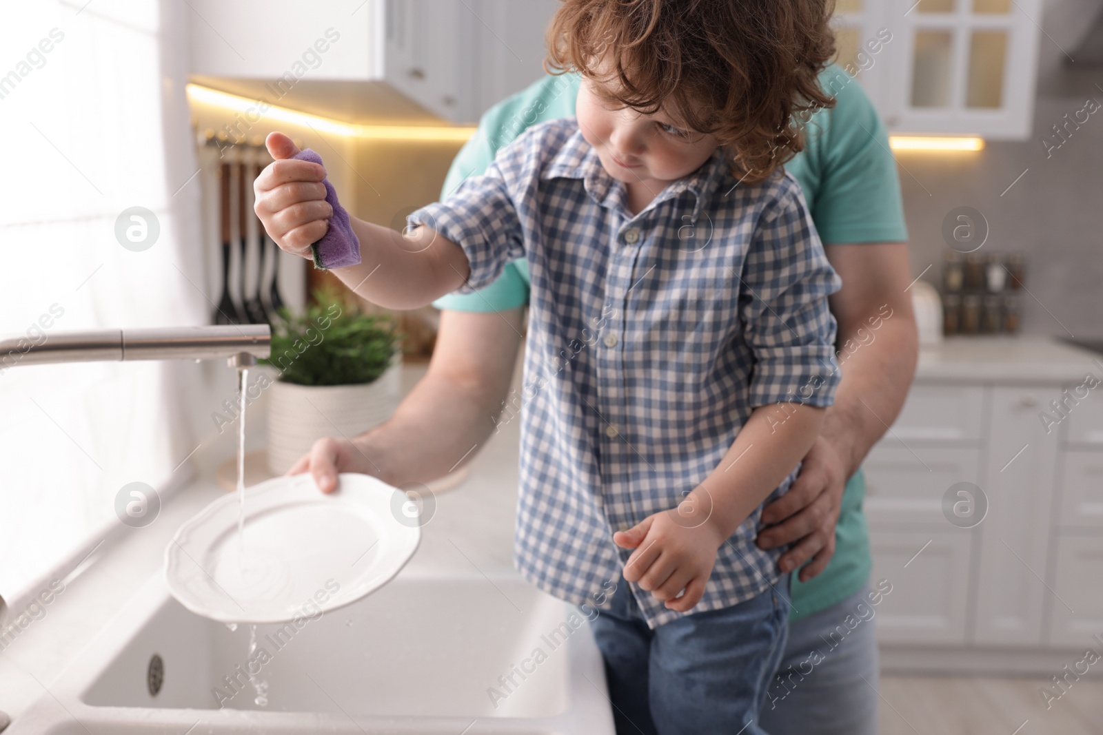 Father and his son washing dishes together in kitchen at home, closeup Photo of Father and his son washing dishes together in kitchen at home, closeup