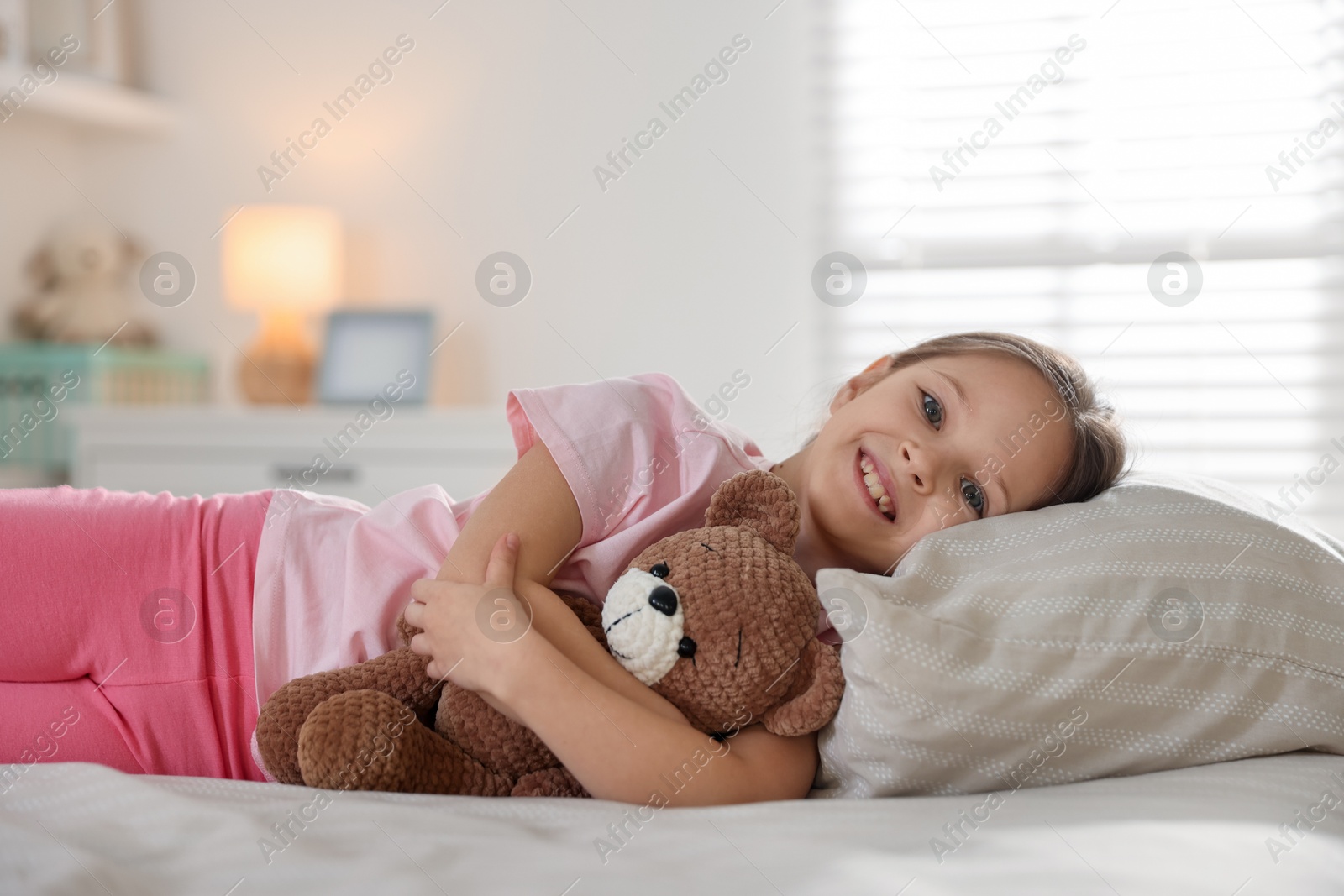Cute girl with teddy bear on bed at home. Space for text Photo of Cute girl with teddy bear on bed at home. Space for text