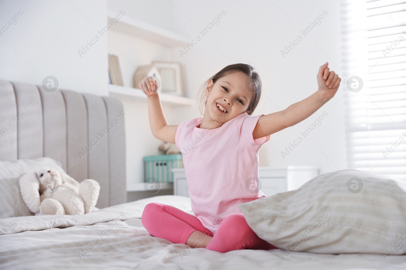 Cute girl with pillow on bed at home Photo of Cute girl with pillow on bed at home
