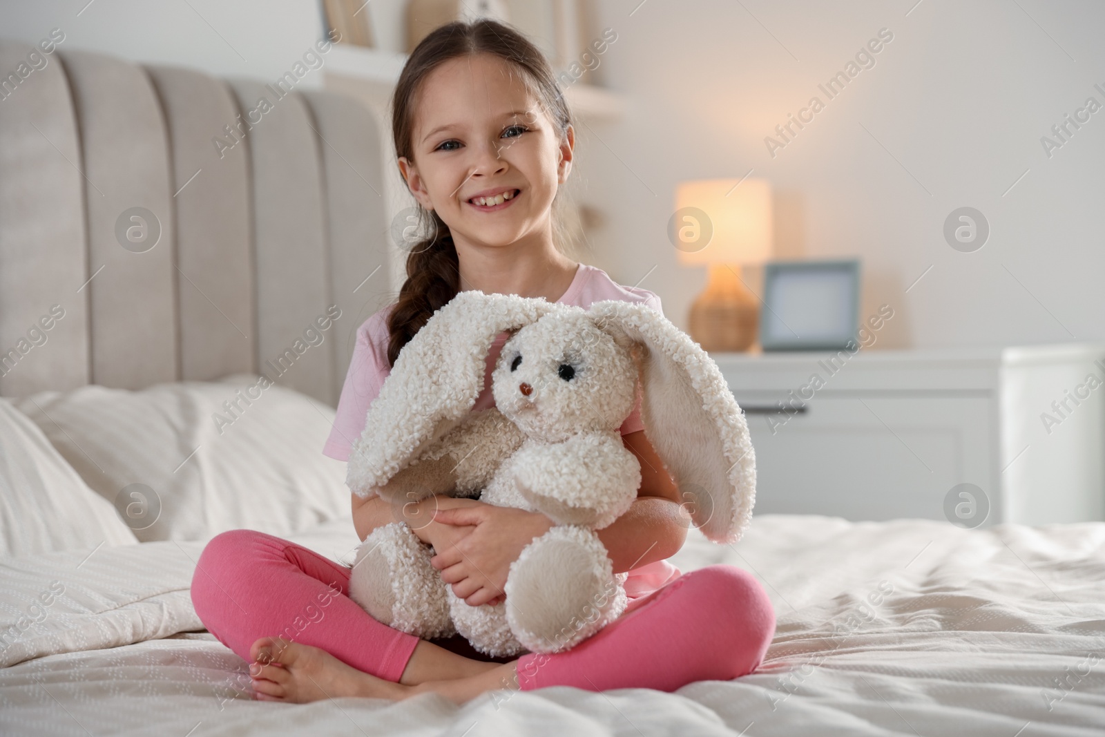 Cute girl with toy bunny on bed at home Photo of Cute girl with toy bunny on bed at home