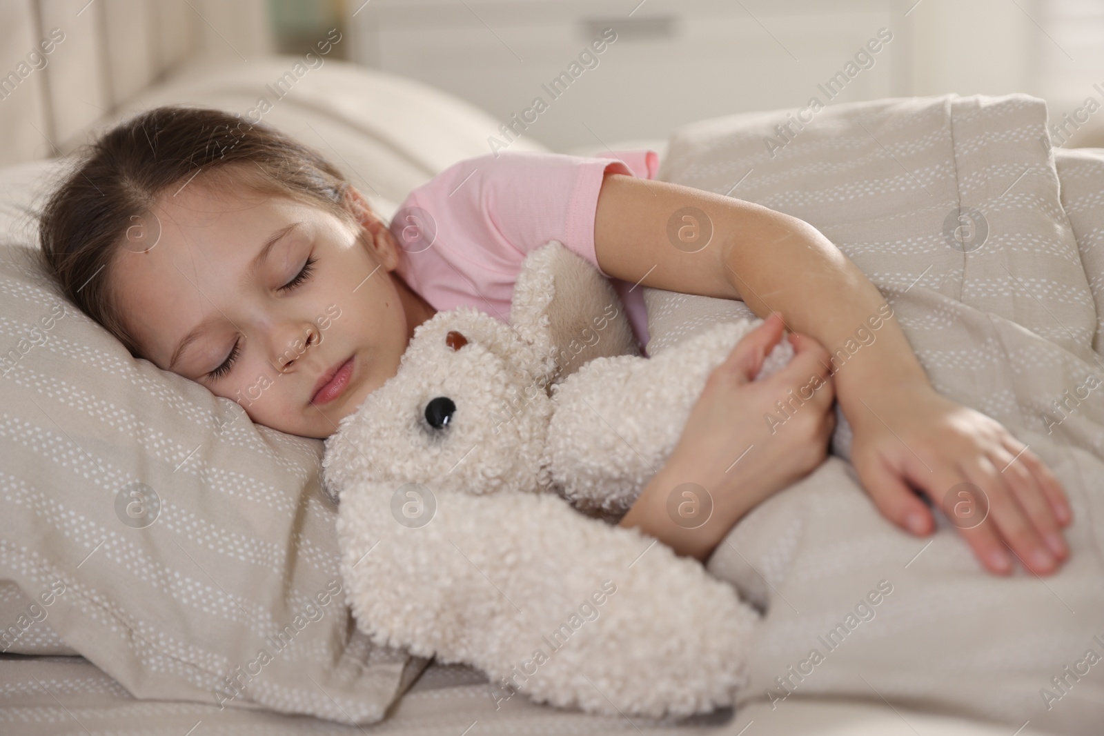 Cute girl with toy bunny sleeping in bed at home Photo of Cute girl with toy bunny sleeping in bed at home
