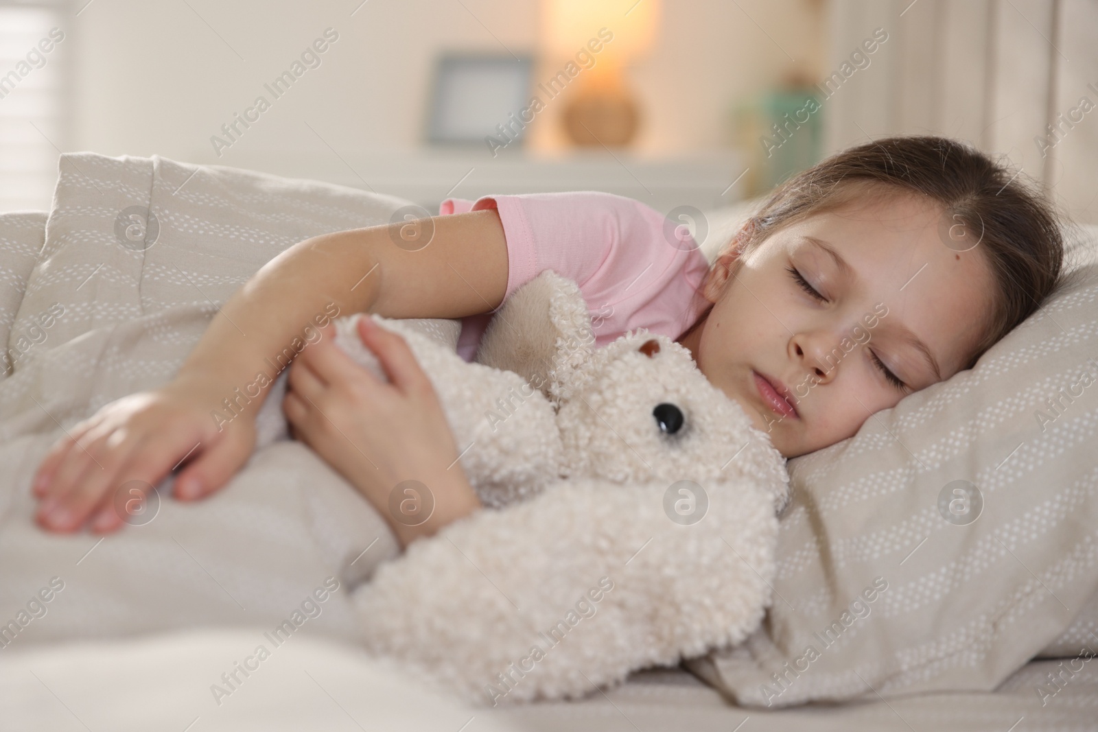 Cute girl with toy bunny sleeping in bed at home Photo of Cute girl with toy bunny sleeping in bed at home