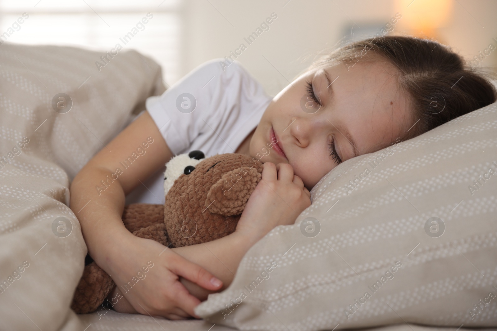 Cute girl with teddy bear sleeping in bed at home Photo of Cute girl with teddy bear sleeping in bed at home