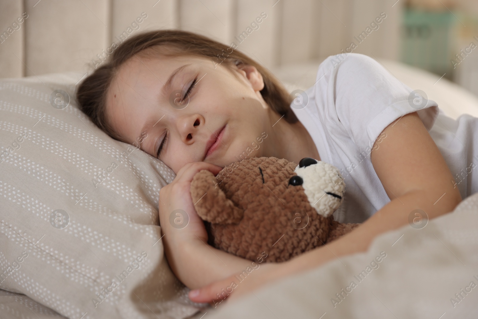 Cute girl with teddy bear sleeping in bed at home Photo of Cute girl with teddy bear sleeping in bed at home