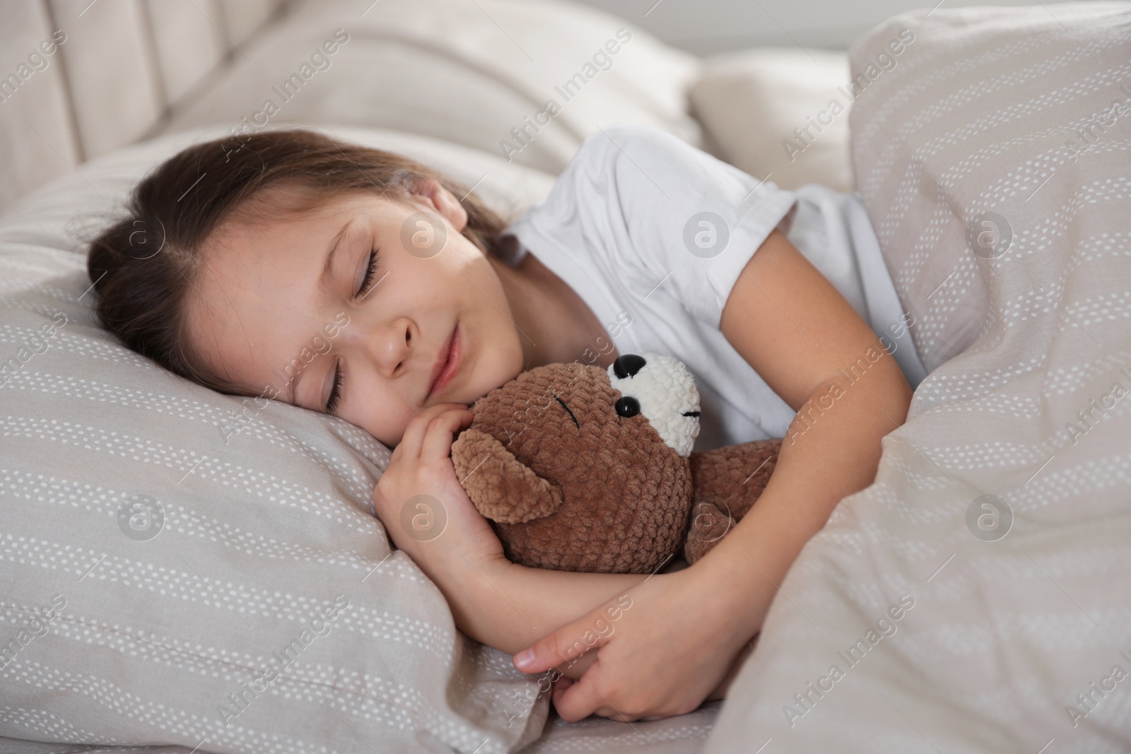Cute girl with teddy bear sleeping in bed at home Photo of Cute girl with teddy bear sleeping in bed at home