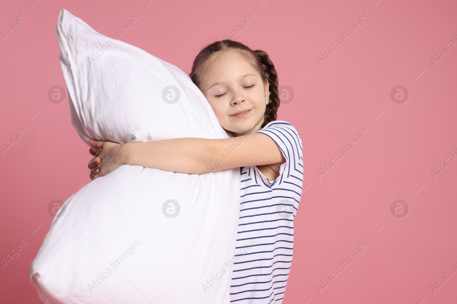 Cute girl with pillow on pink background Photo of Cute girl with pillow on pink background