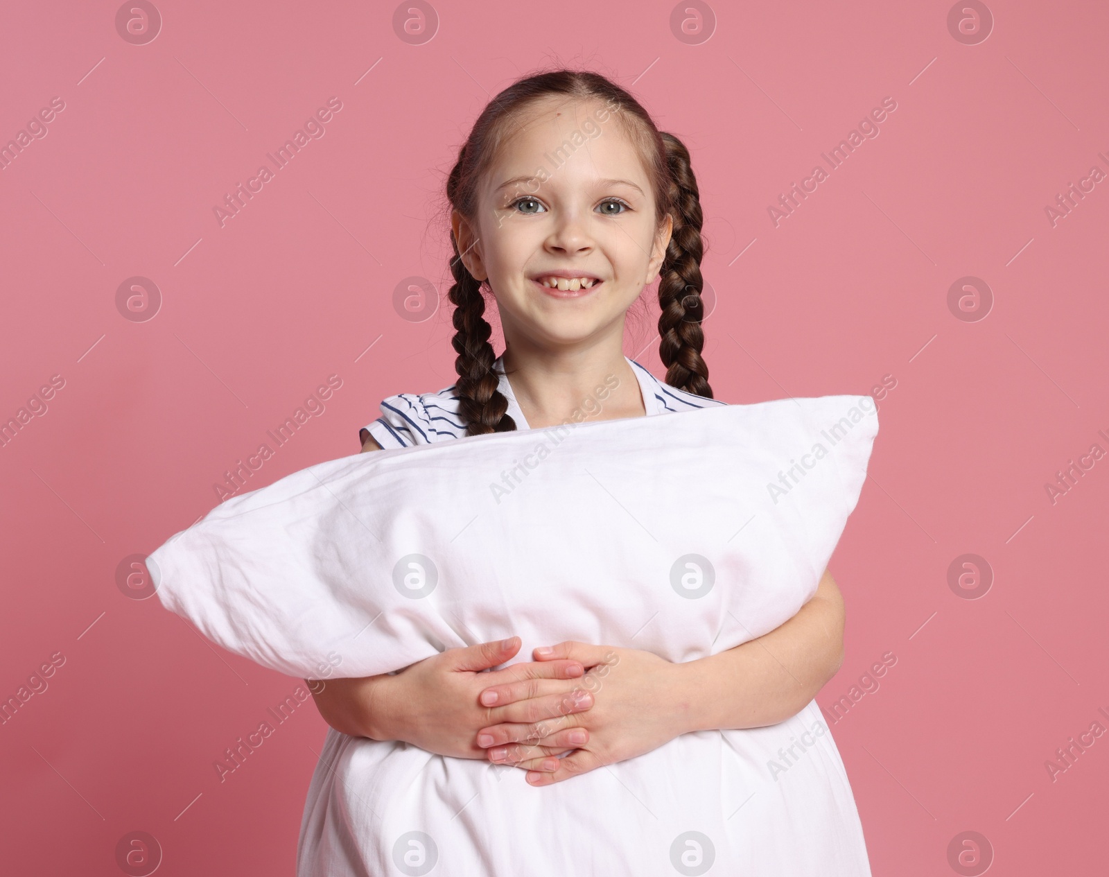 Cute girl with pillow on pink background Photo of Cute girl with pillow on pink background