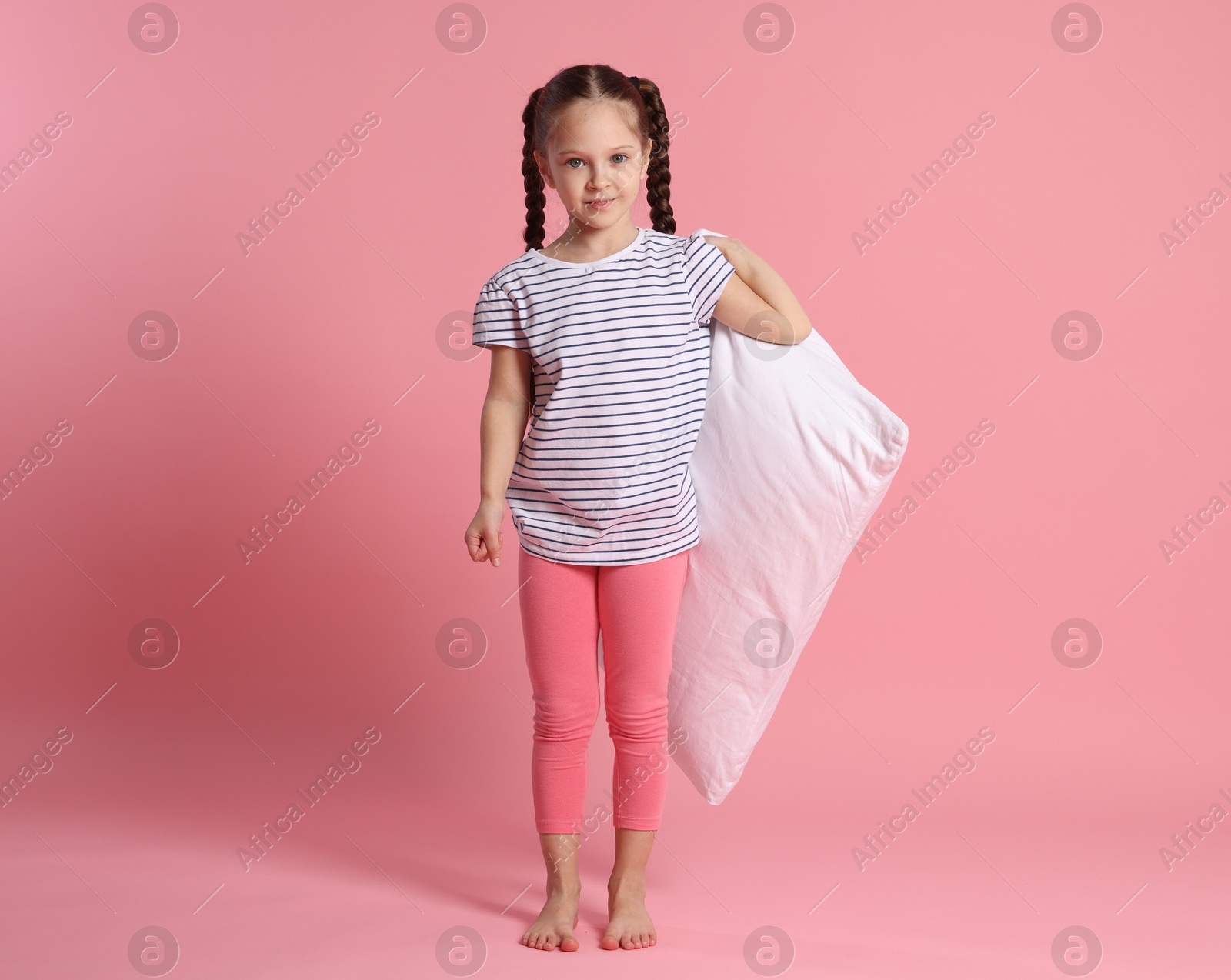 Cute girl with pillow on pink background Photo of Cute girl with pillow on pink background