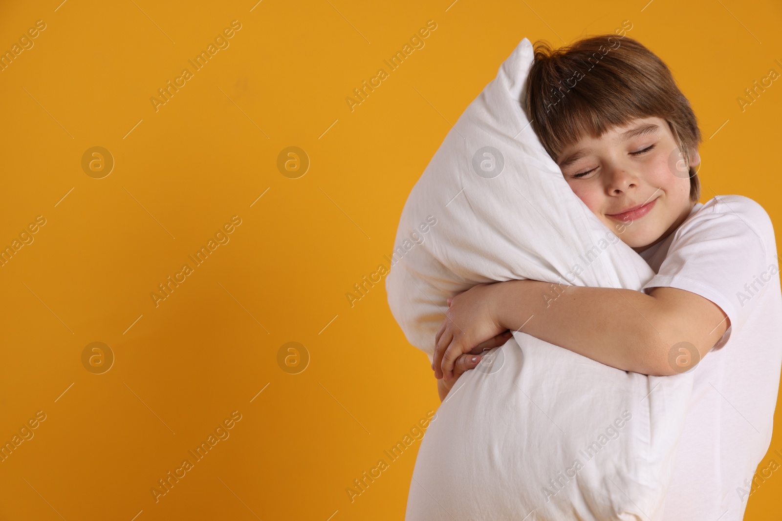Cute boy with pillow on orange background. Space for text Photo of Cute boy with pillow on orange background. Space for text