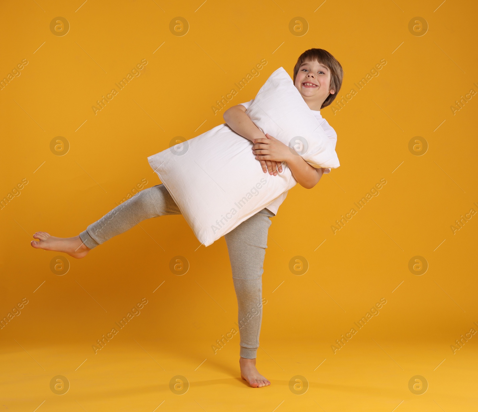 Cute boy with pillow on orange background Photo of Cute boy with pillow on orange background