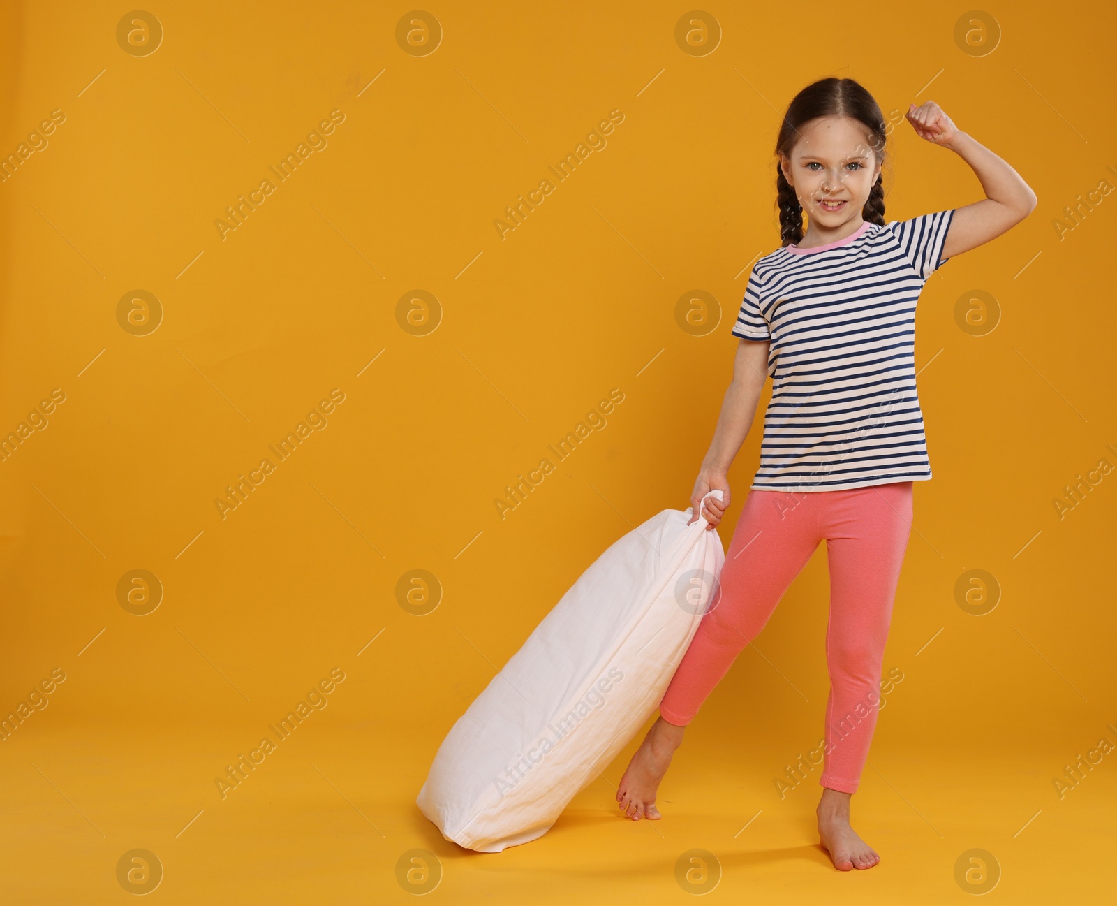 Cute girl with pillow on orange background. Space for text Photo of Cute girl with pillow on orange background. Space for text