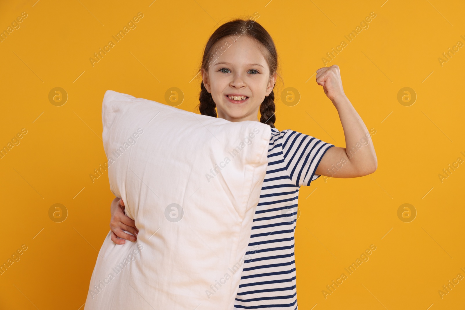 Cute girl with pillow on orange background Photo of Cute girl with pillow on orange background