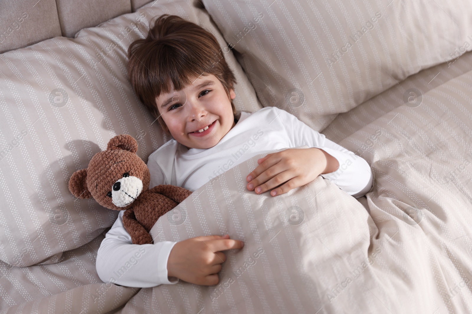 Cute boy with teddy bear in bed Photo of Cute boy with teddy bear in bed