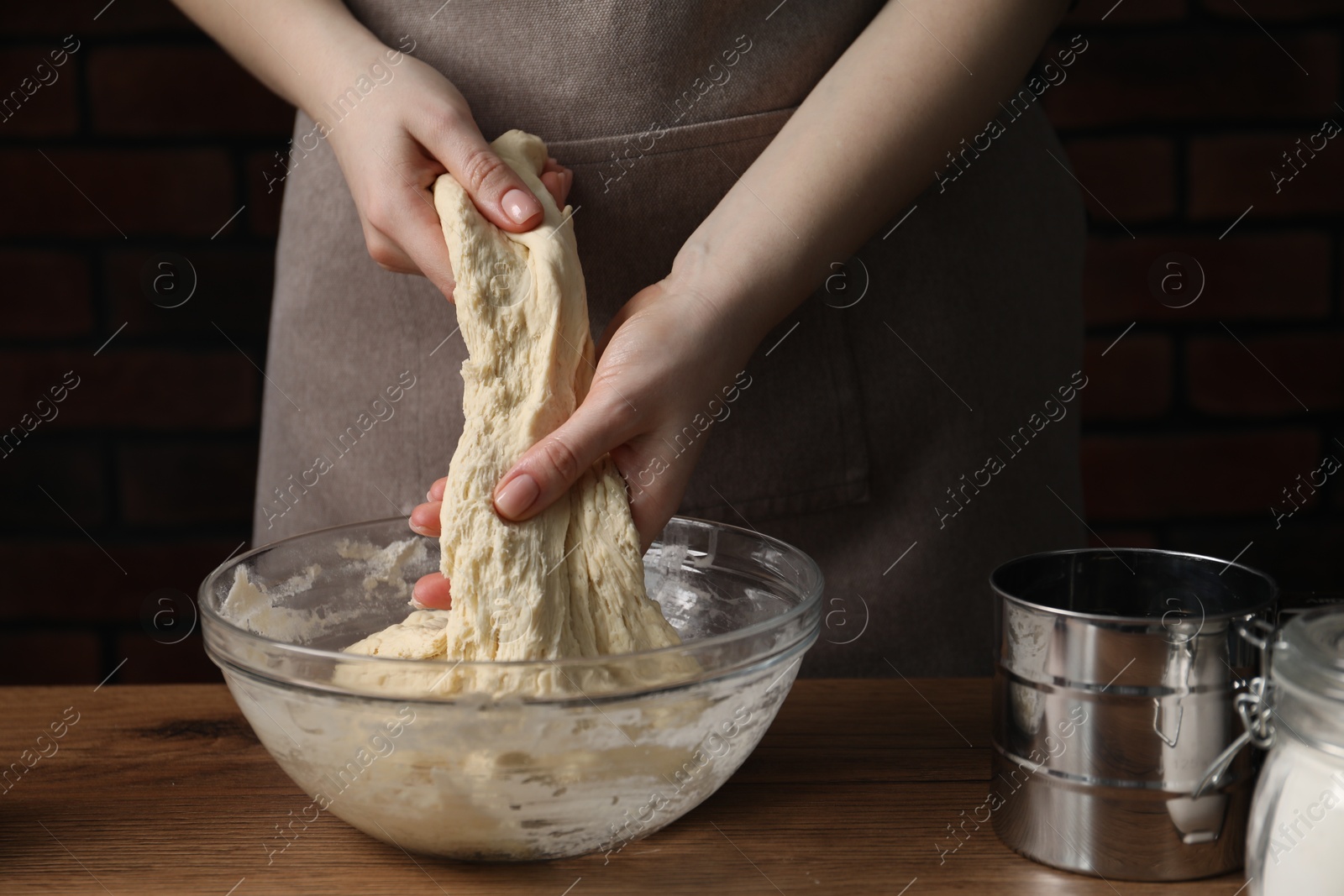 Woman kneading raw dough at wooden table, closeup Photo of Woman kneading raw dough at wooden table, closeup