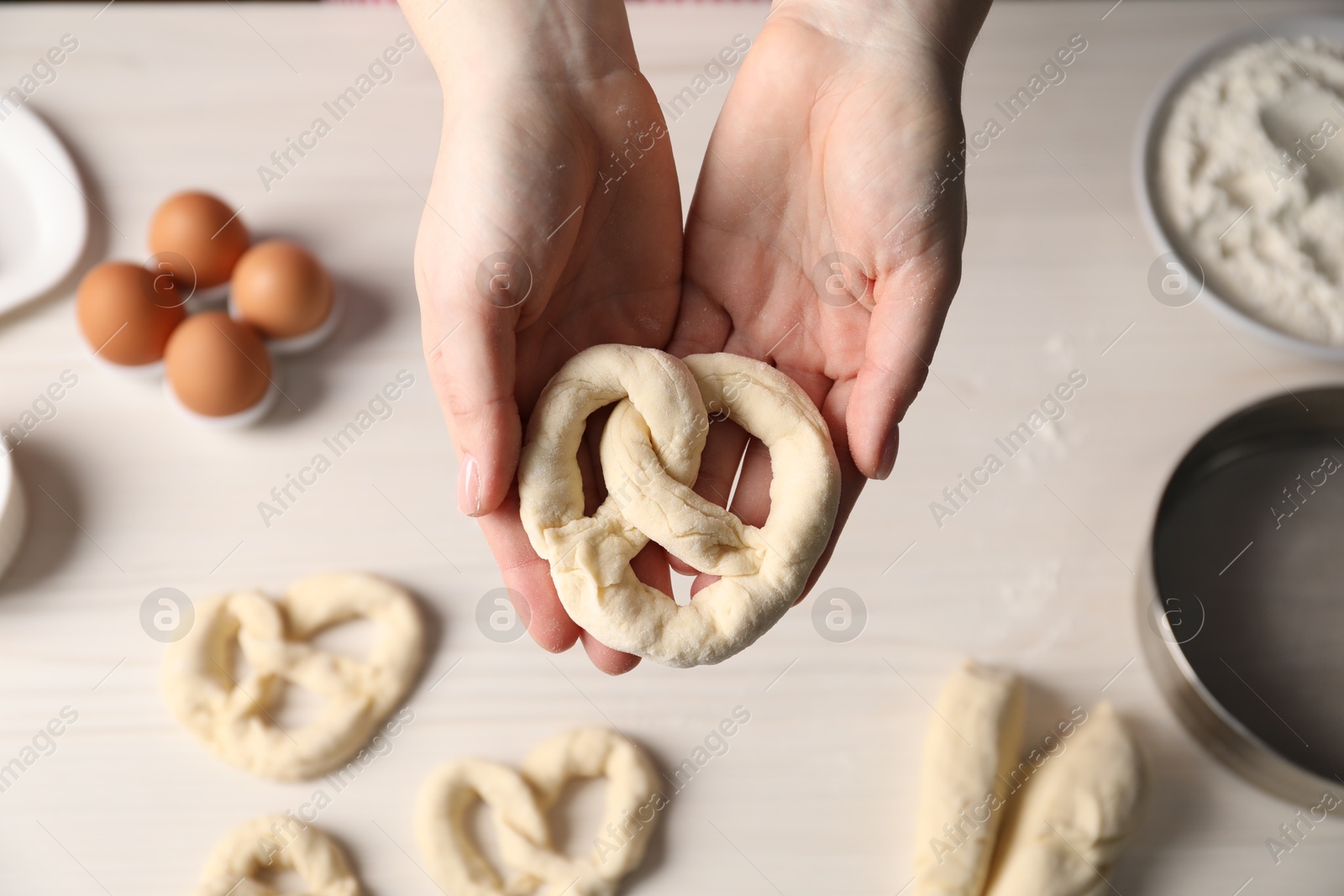 Woman making pretzels at white wooden table, top view Photo of Woman making pretzels at white wooden table, top view