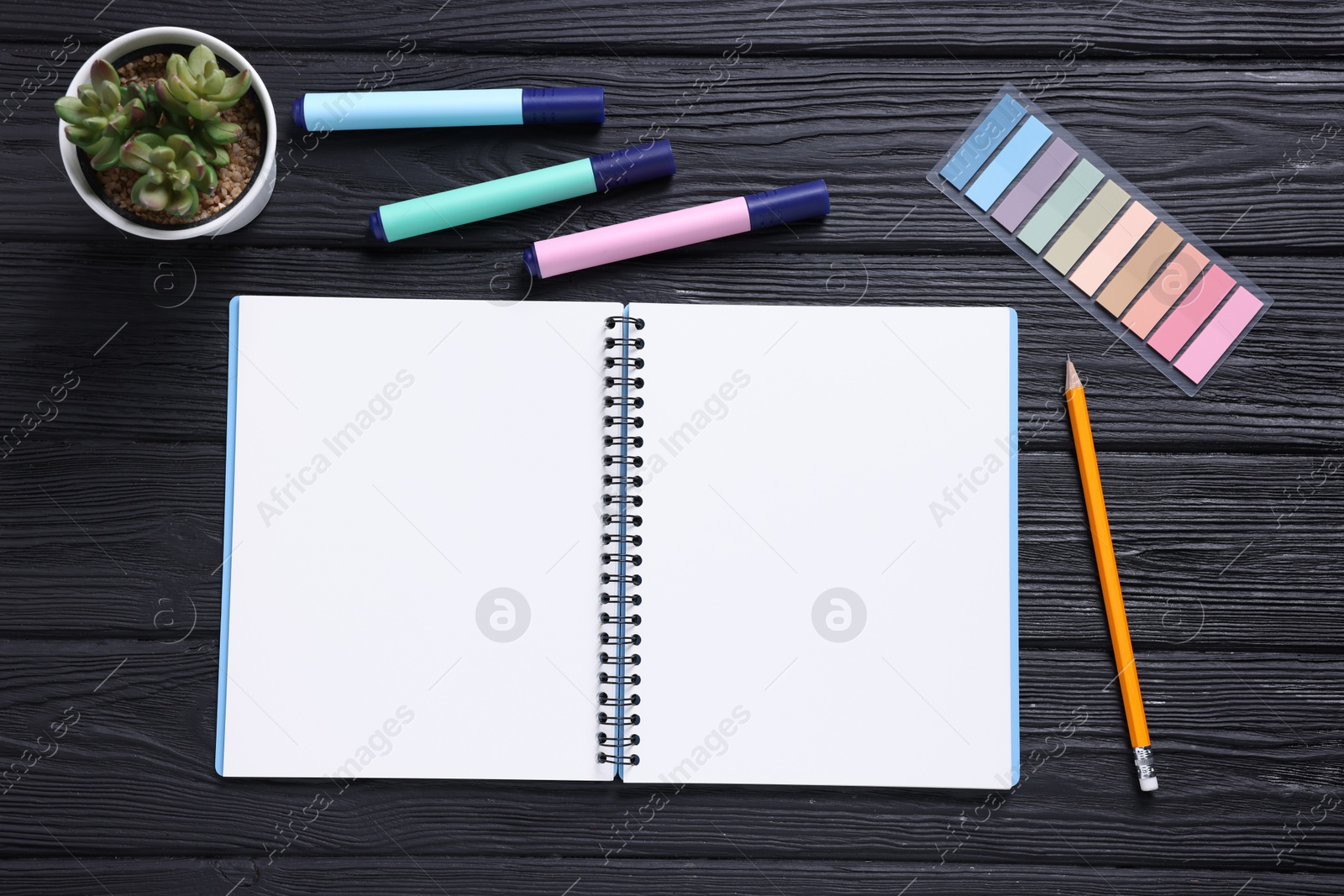 Open blank notebook, houseplant, pencil, markers and bookmarks on black wooden table, flat lay Photo of Open blank notebook, houseplant, pencil, markers and bookmarks on black wooden table, flat lay