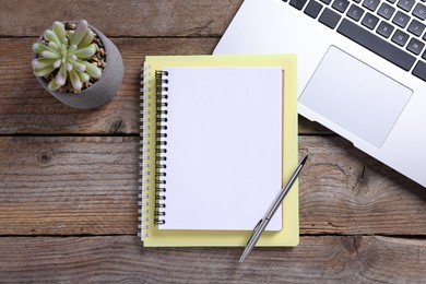 Photo of Blank notebooks, laptop, houseplant and pen on wooden table, flat lay