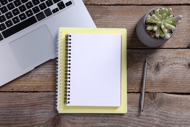 Photo of Blank notebooks, laptop, houseplant and pen on wooden table, flat lay