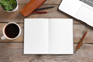 Photo of Open blank notebook, coffee, houseplant, laptop and pens on wooden table, flat lay