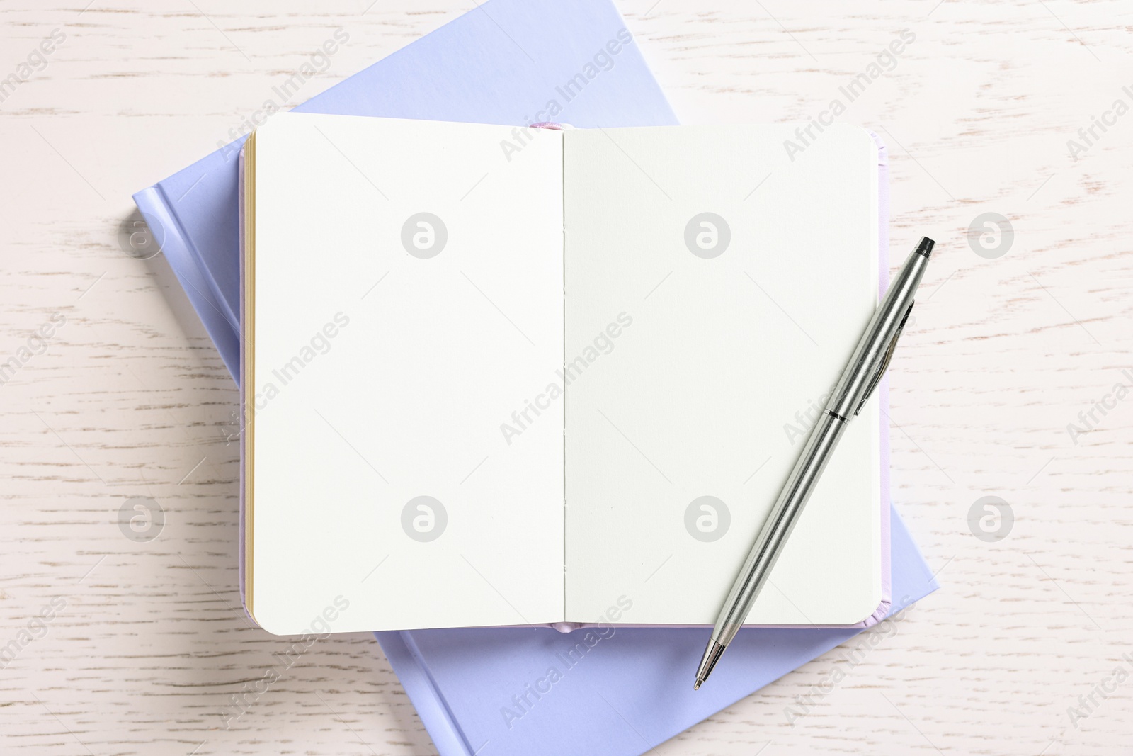 Photo of Blank notebooks and pen on white wooden table, top view