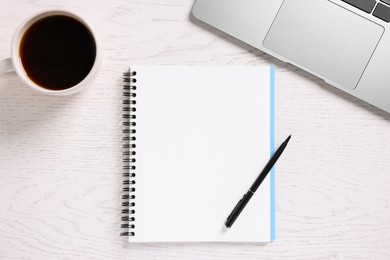 Photo of Blank notebook, coffee, laptop and pen on white wooden table, flat lay