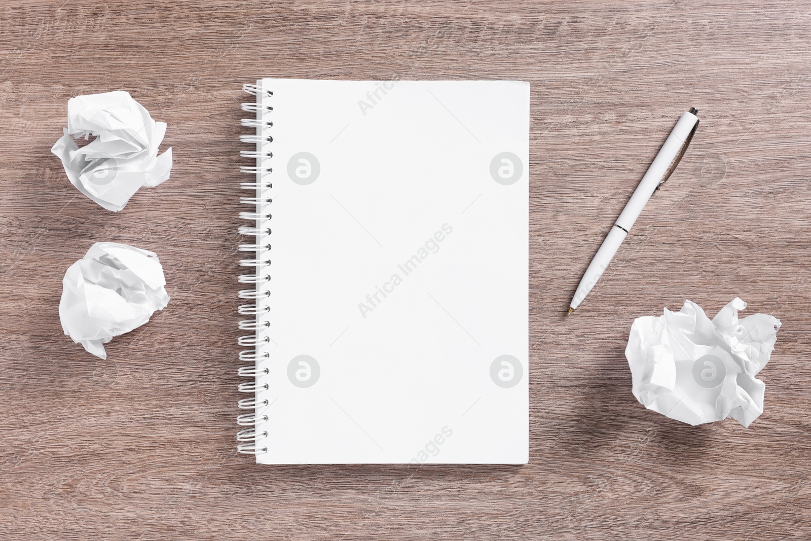 Open blank notebook, crumpled paper and pen on wooden table, flat lay Photo of Open blank notebook, crumpled paper and pen on wooden table, flat lay