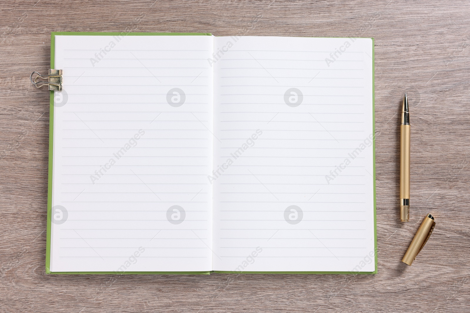 Open blank notebook, binder clip and pen on wooden table, top view Photo of Open blank notebook, binder clip and pen on wooden table, top view