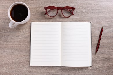 Photo of Open blank notebook, coffee, pen and glasses on wooden table, flat lay