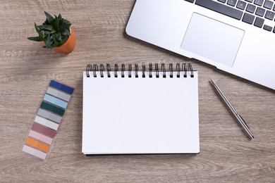 Photo of Open blank notebook, houseplant, laptop and stationery on wooden table, flat lay