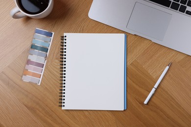 Photo of Open blank notebook, coffee, laptop, bookmarks and pen on wooden table, flat lay