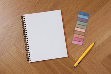 Photo of Open blank notebook, bookmarks and pen on wooden table, flat lay