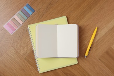 Photo of Blank notebooks, bookmarks and pen on wooden table, flat lay