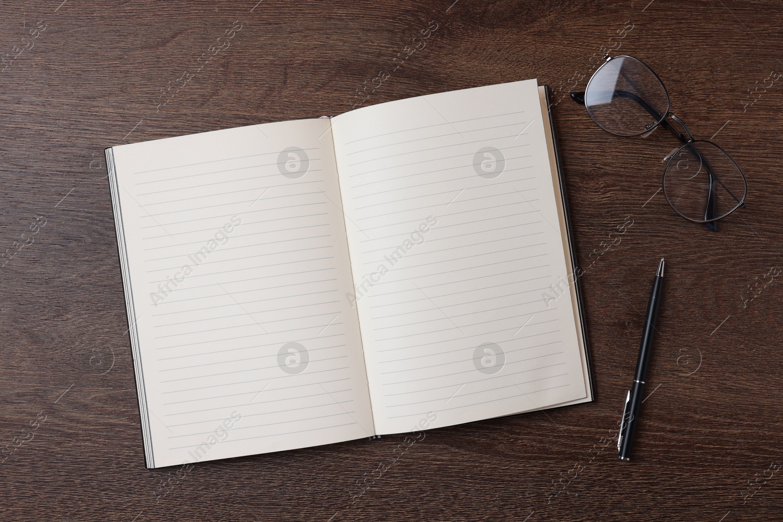 Open blank notebook, pen and glasses on wooden table, flat lay Photo of Open blank notebook, pen and glasses on wooden table, flat lay