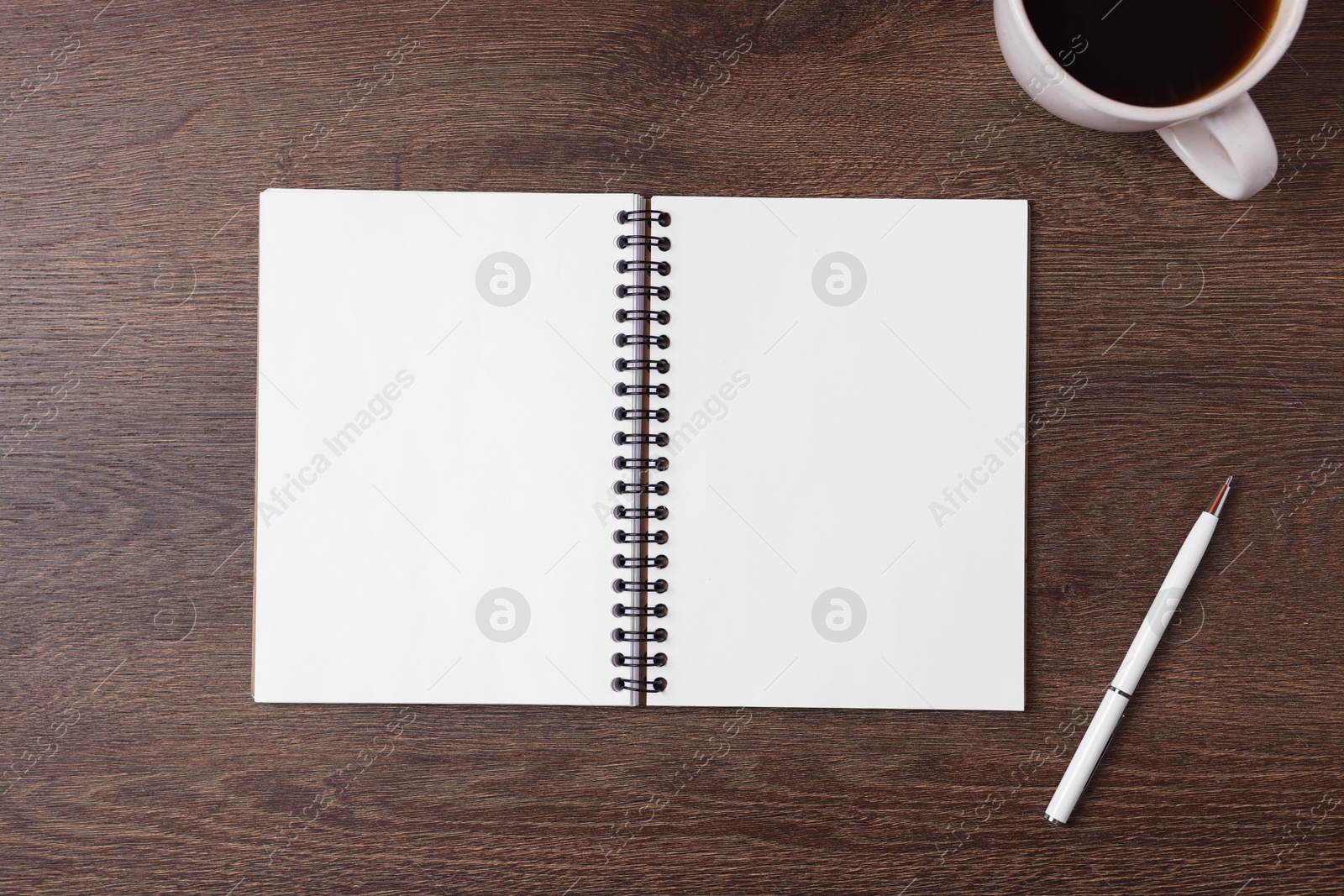 Open blank notebook, pen and coffee on wooden table, flat lay Photo of Open blank notebook, pen and coffee on wooden table, flat lay