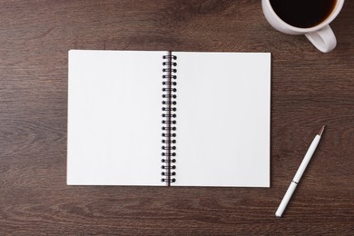 Photo of Open blank notebook, pen and coffee on wooden table, flat lay