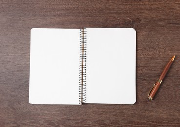 Photo of Open blank notebook and pen on wooden table, top view