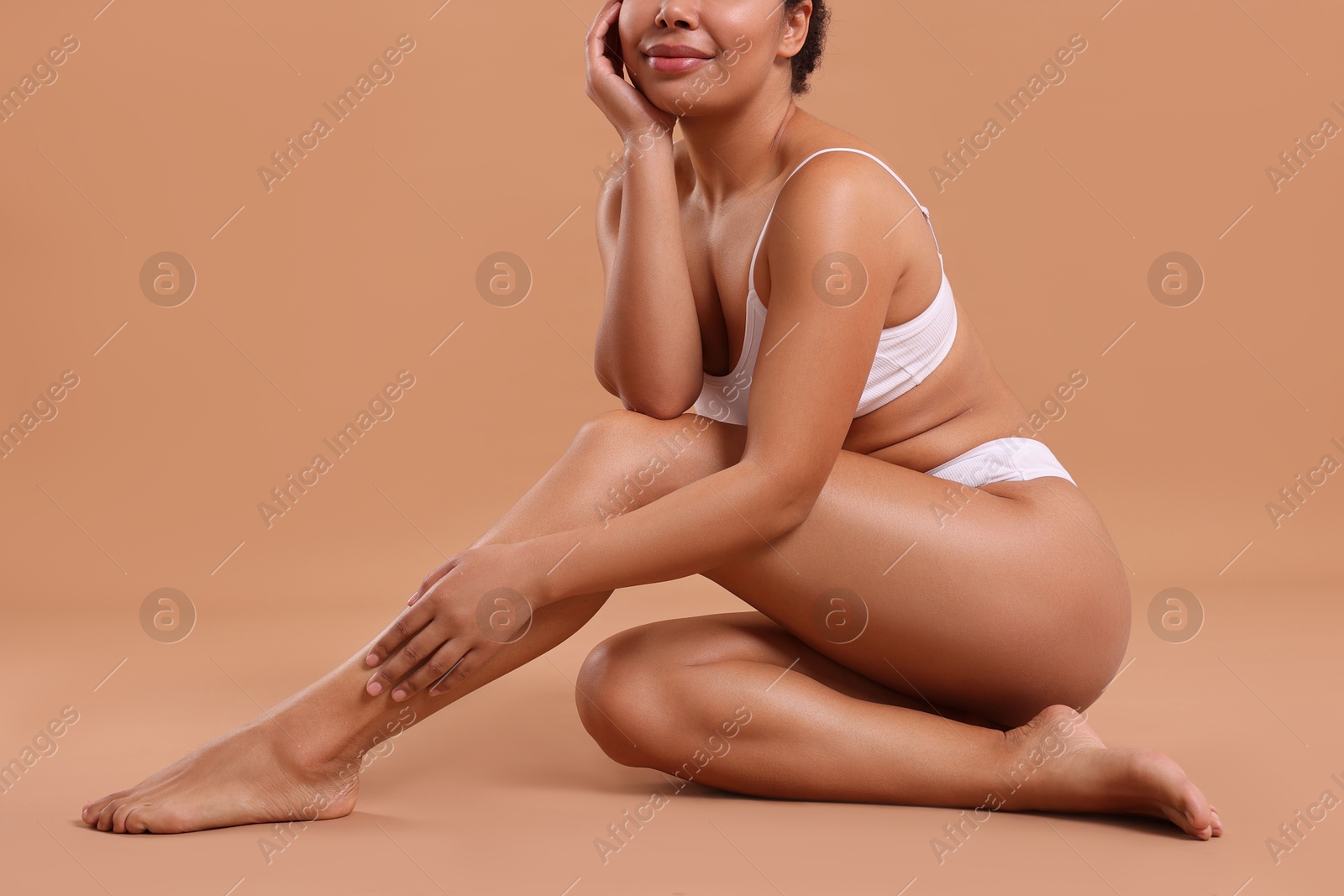 Photo of Woman in white underwear with smooth skin after epilation procedure on beige background, closeup