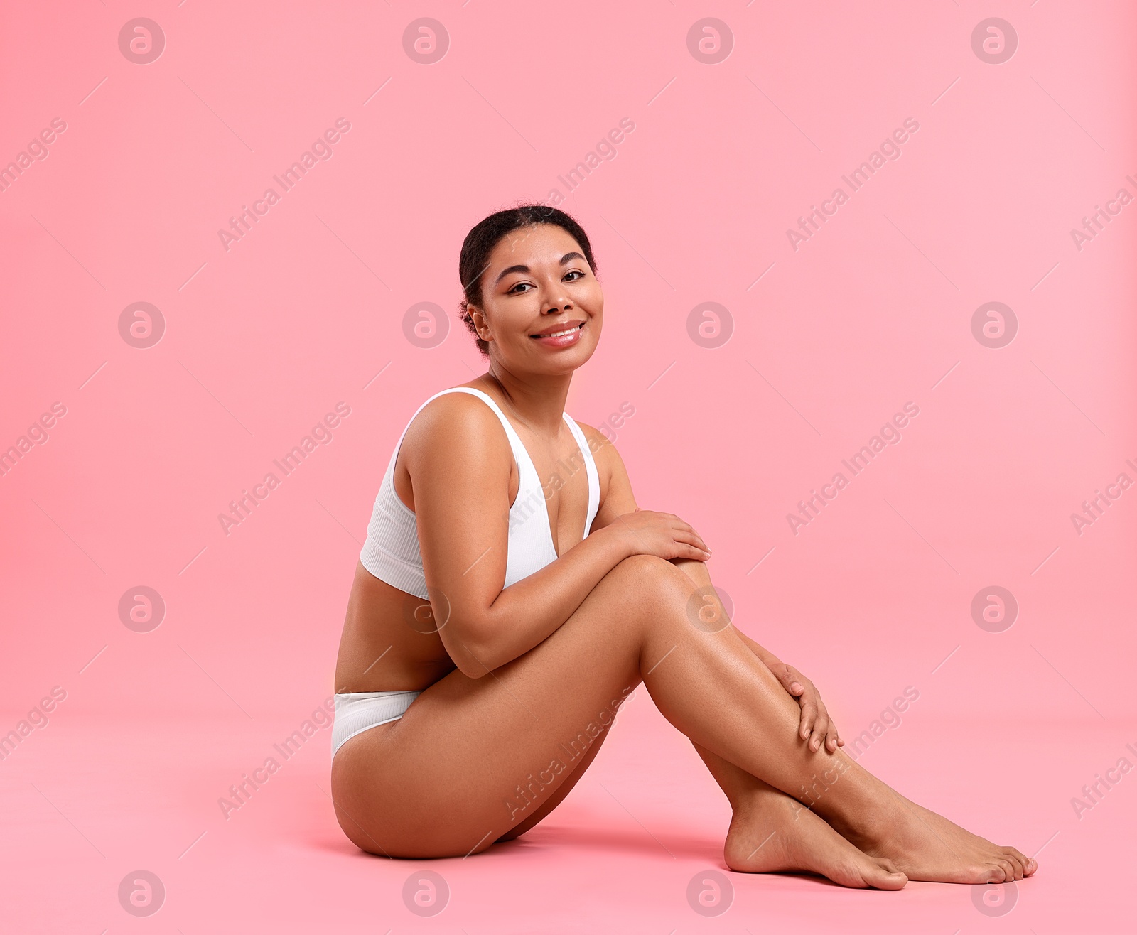 Woman in white underwear with smooth skin after epilation procedure on pink background Photo of Woman in white underwear with smooth skin after epilation procedure on pink background