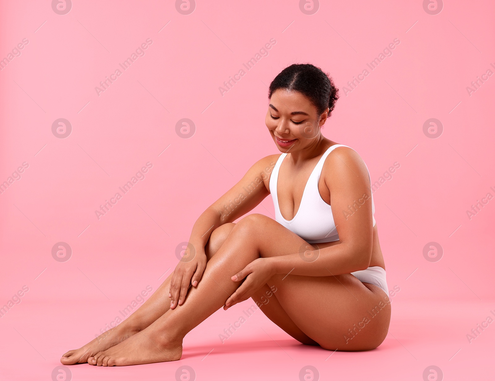 Woman in white underwear with smooth skin after epilation procedure on pink background Photo of Woman in white underwear with smooth skin after epilation procedure on pink background