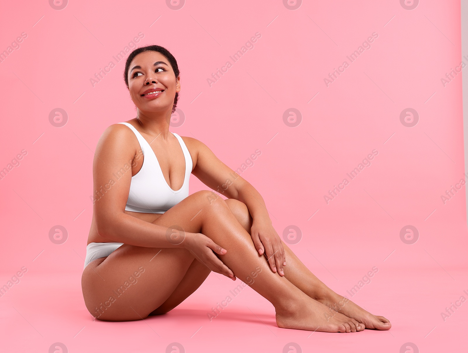 Woman in white underwear with smooth skin after epilation procedure on pink background Photo of Woman in white underwear with smooth skin after epilation procedure on pink background