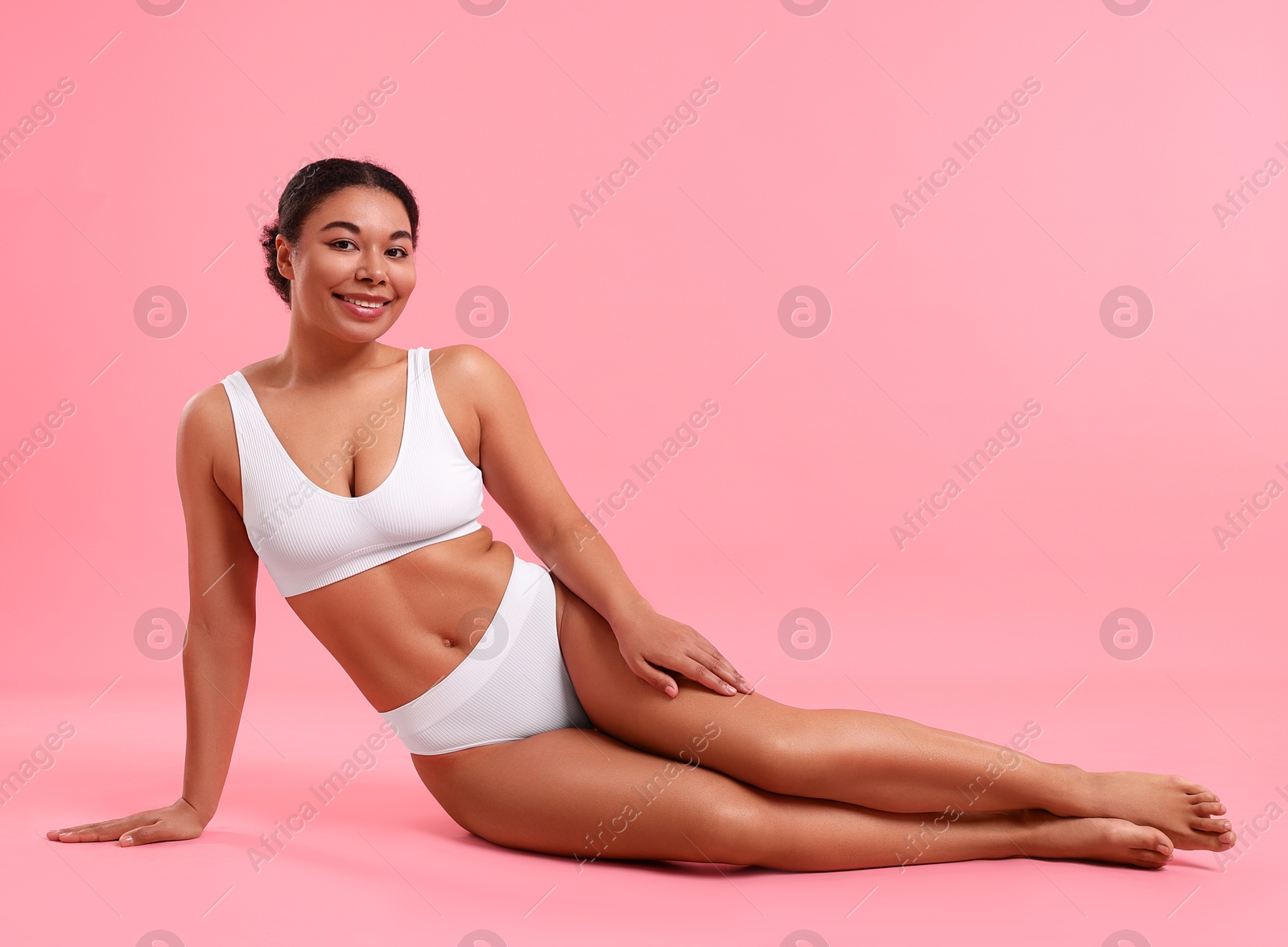 Woman in white underwear with smooth skin after epilation procedure on pink background Photo of Woman in white underwear with smooth skin after epilation procedure on pink background