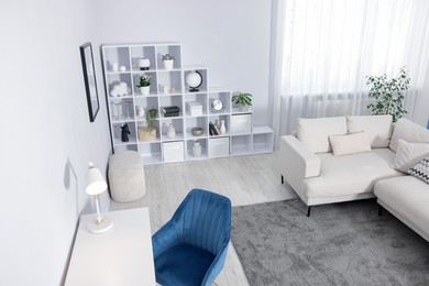 Photo of Comfortable sofa, shelving unit, table and armchair in living room, above view