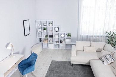 Photo of Comfortable sofa, shelving unit, table and armchair in living room, above view