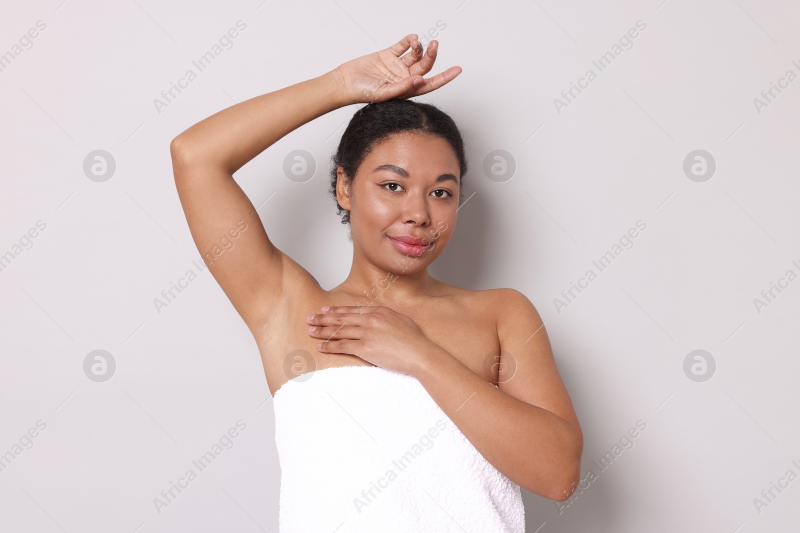 Woman showing hairless armpit after epilation procedure on light grey background Photo of Woman showing hairless armpit after epilation procedure on light grey background