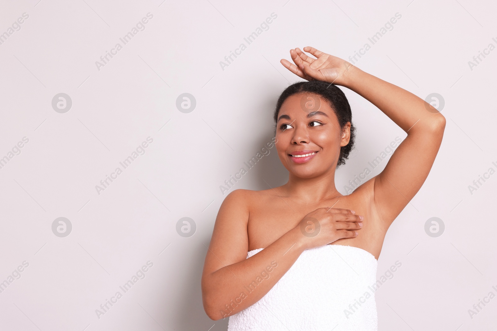 Woman showing hairless armpit after epilation procedure on light grey background, space for text Photo of Woman showing hairless armpit after epilation procedure on light grey background, space for text