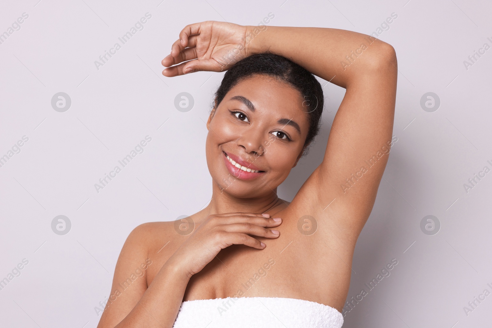 Woman showing hairless armpit after epilation procedure on light grey background Photo of Woman showing hairless armpit after epilation procedure on light grey background