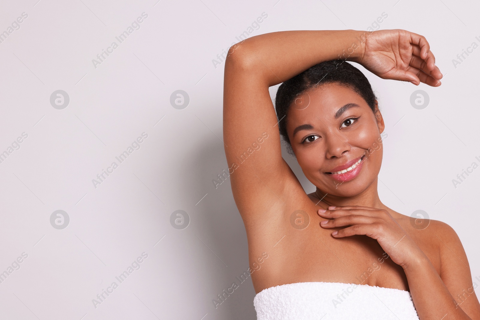 Woman showing hairless armpit after epilation procedure on light grey background, space for text Photo of Woman showing hairless armpit after epilation procedure on light grey background, space for text