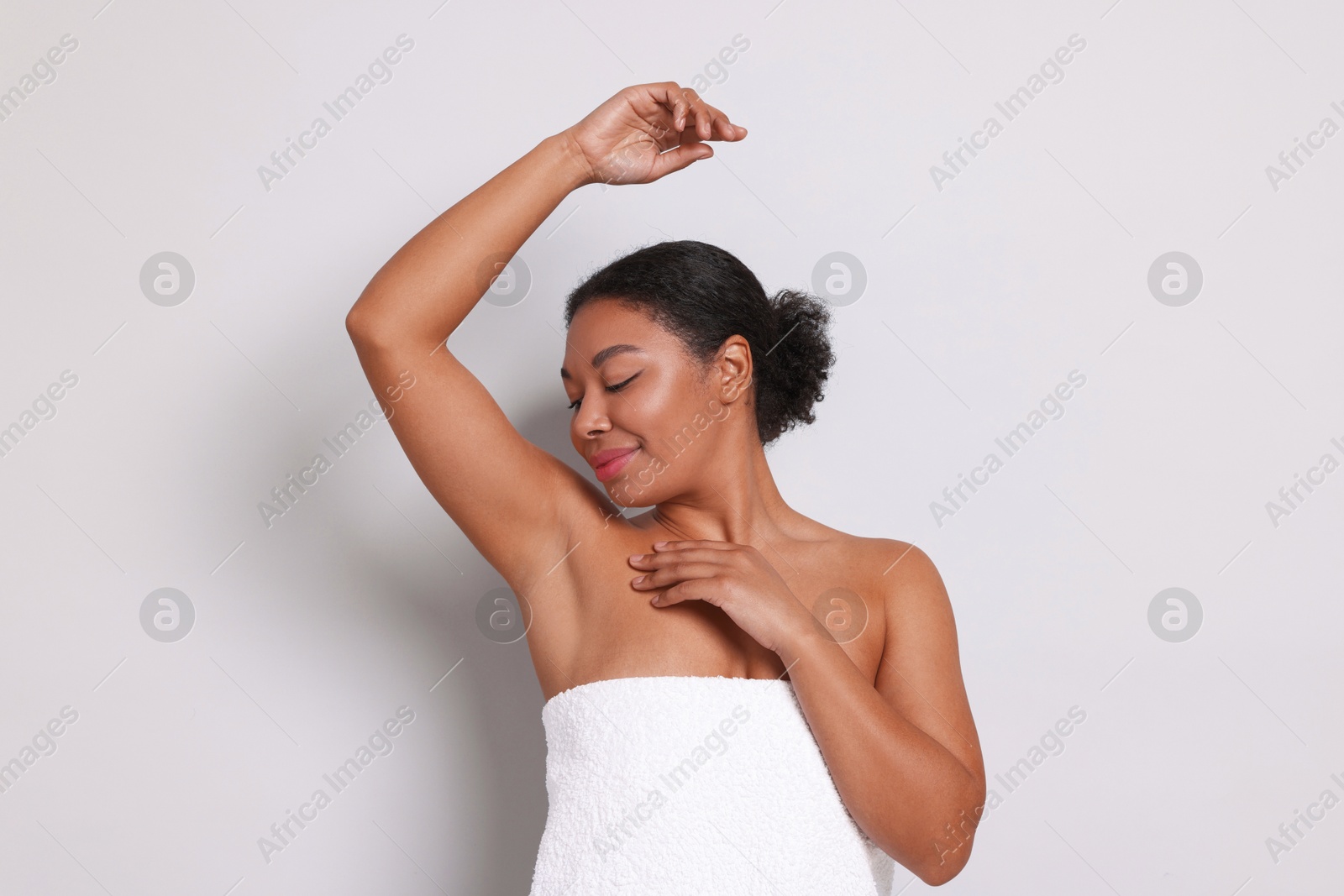 Woman showing hairless armpit after epilation procedure on light grey background Photo of Woman showing hairless armpit after epilation procedure on light grey background