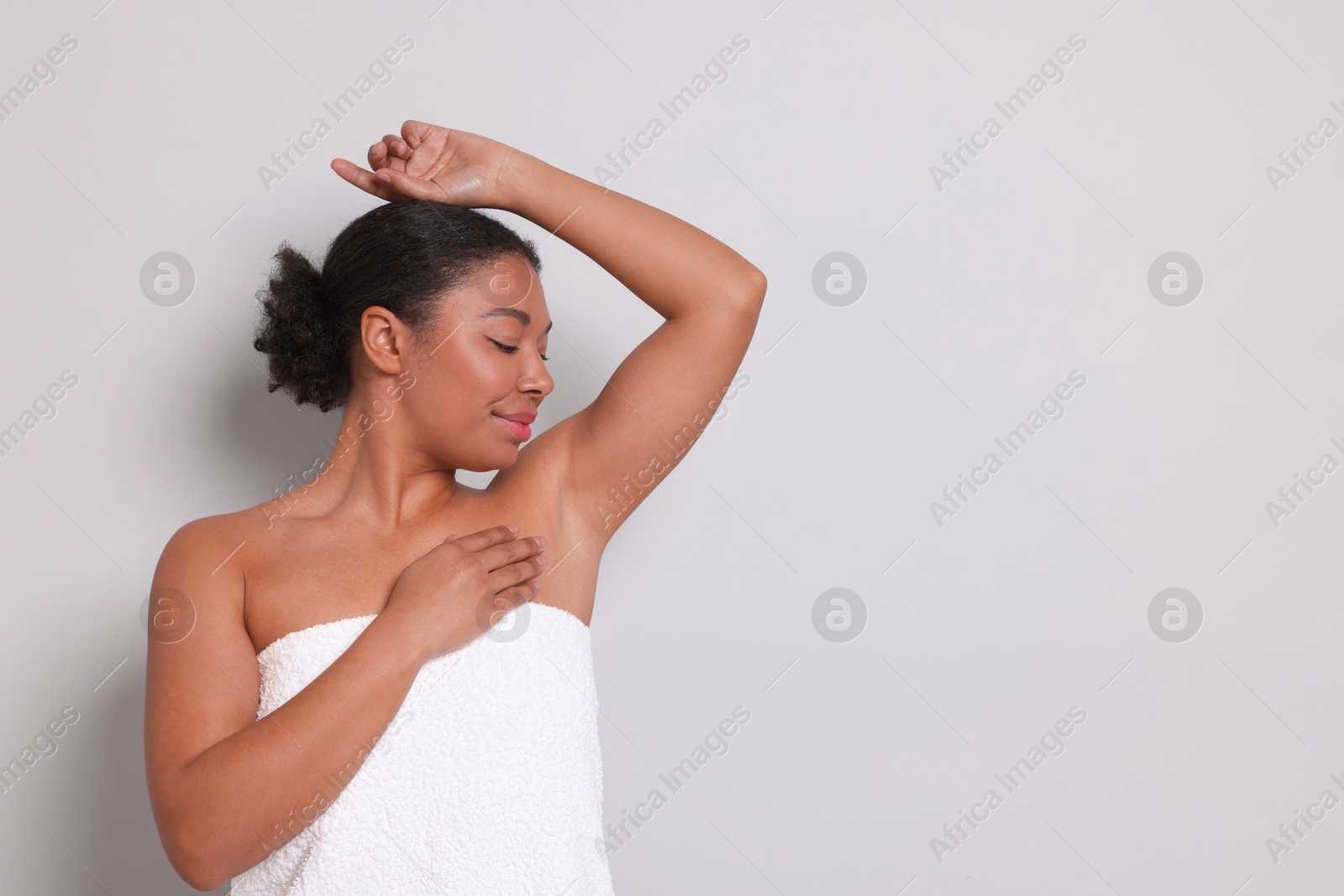 Woman showing hairless armpit after epilation procedure on light grey background, space for text Photo of Woman showing hairless armpit after epilation procedure on light grey background, space for text