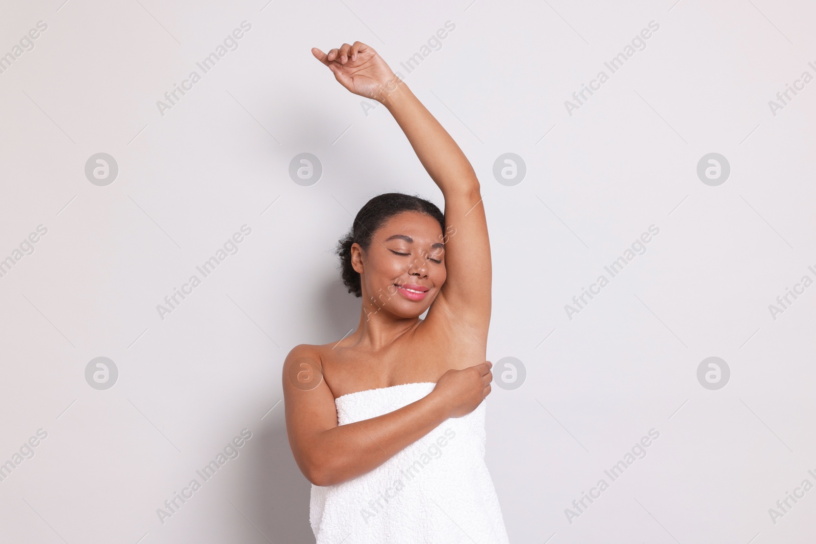 Woman showing hairless armpit after epilation procedure on light grey background Photo of Woman showing hairless armpit after epilation procedure on light grey background